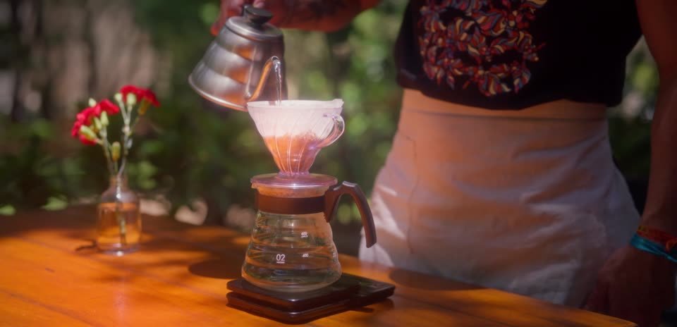 Café coado no filtro, ao lado de flores
